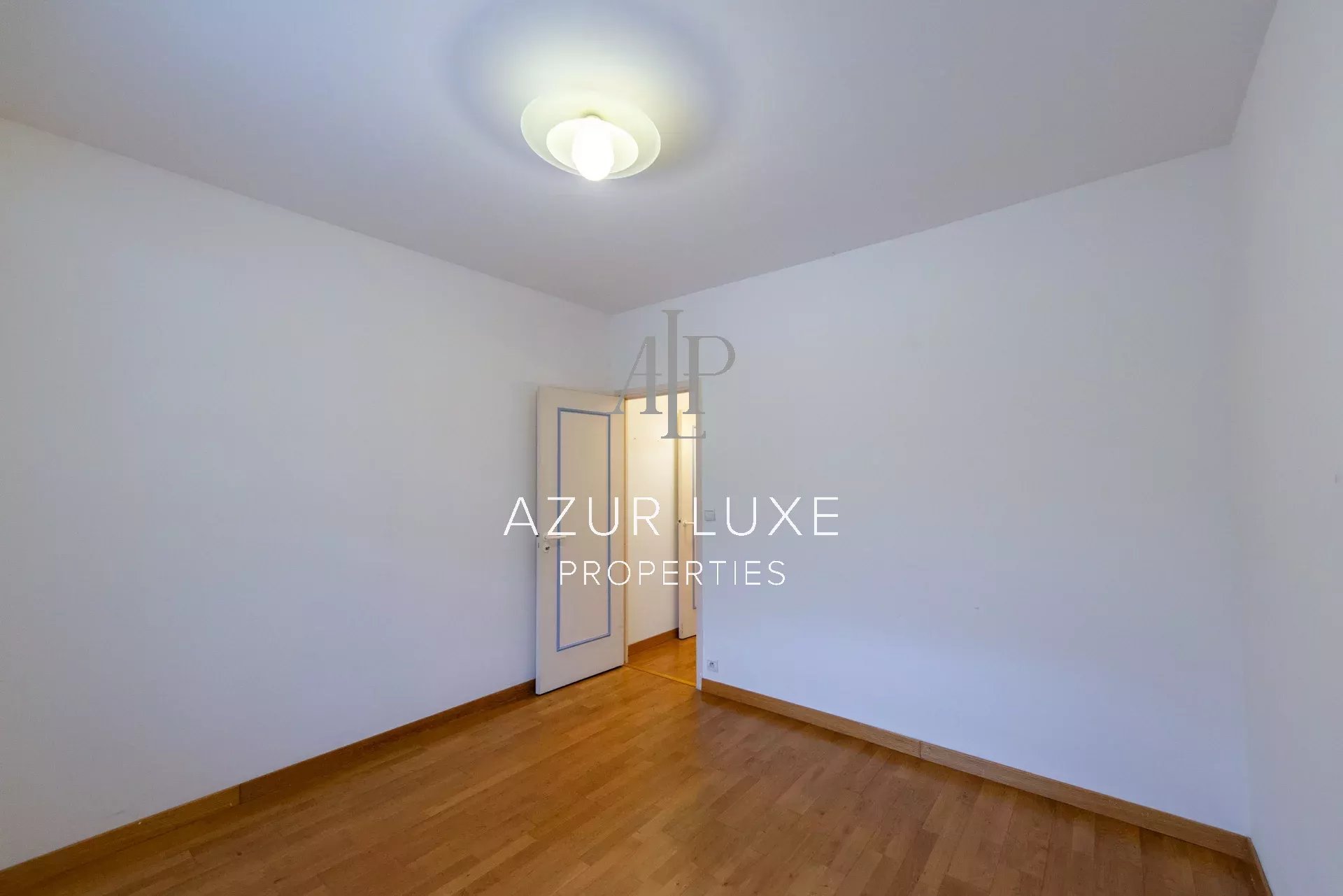 Apartment to renovate in Beaulieu-sur-Mer Interior of an apartment to be renovated with a wooden floor and an open door to another room.