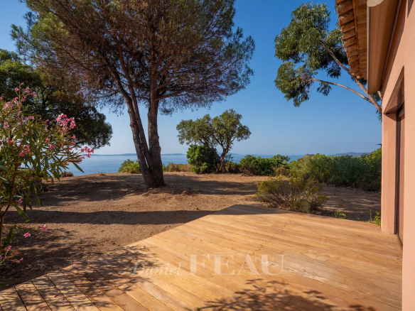 Wooden terrace with sea view in Rayol-Canadel-sur-Mer, surrounded by trees and vegetation.
