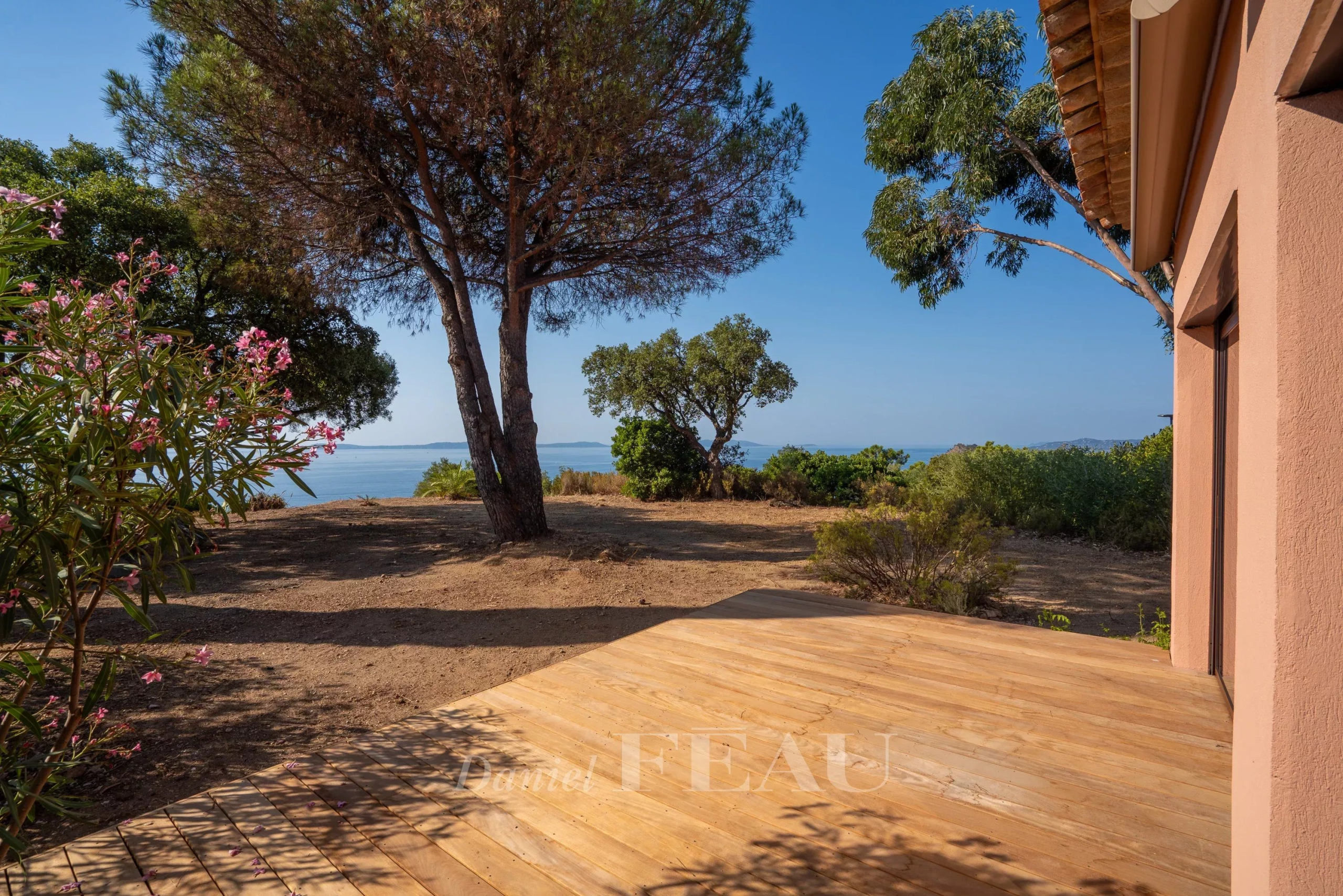 Villa with sea view in Rayol-Canadel-sur-Mer Wooden terrace with sea view in Rayol-Canadel-sur-Mer, surrounded by trees and vegetation.