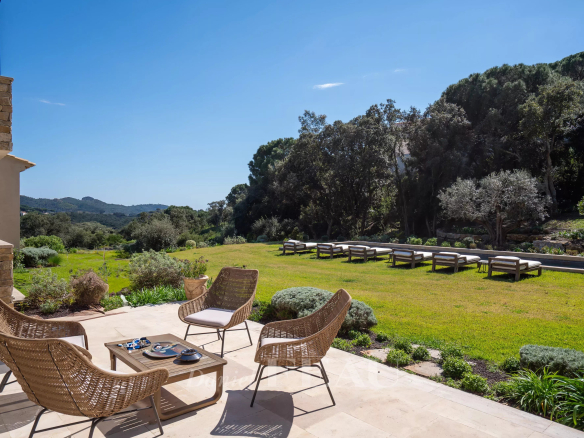 Terrasse d'une propriété moderne avec des fauteuils en osier et un jardin verdoyant à La Croix-Valmer.