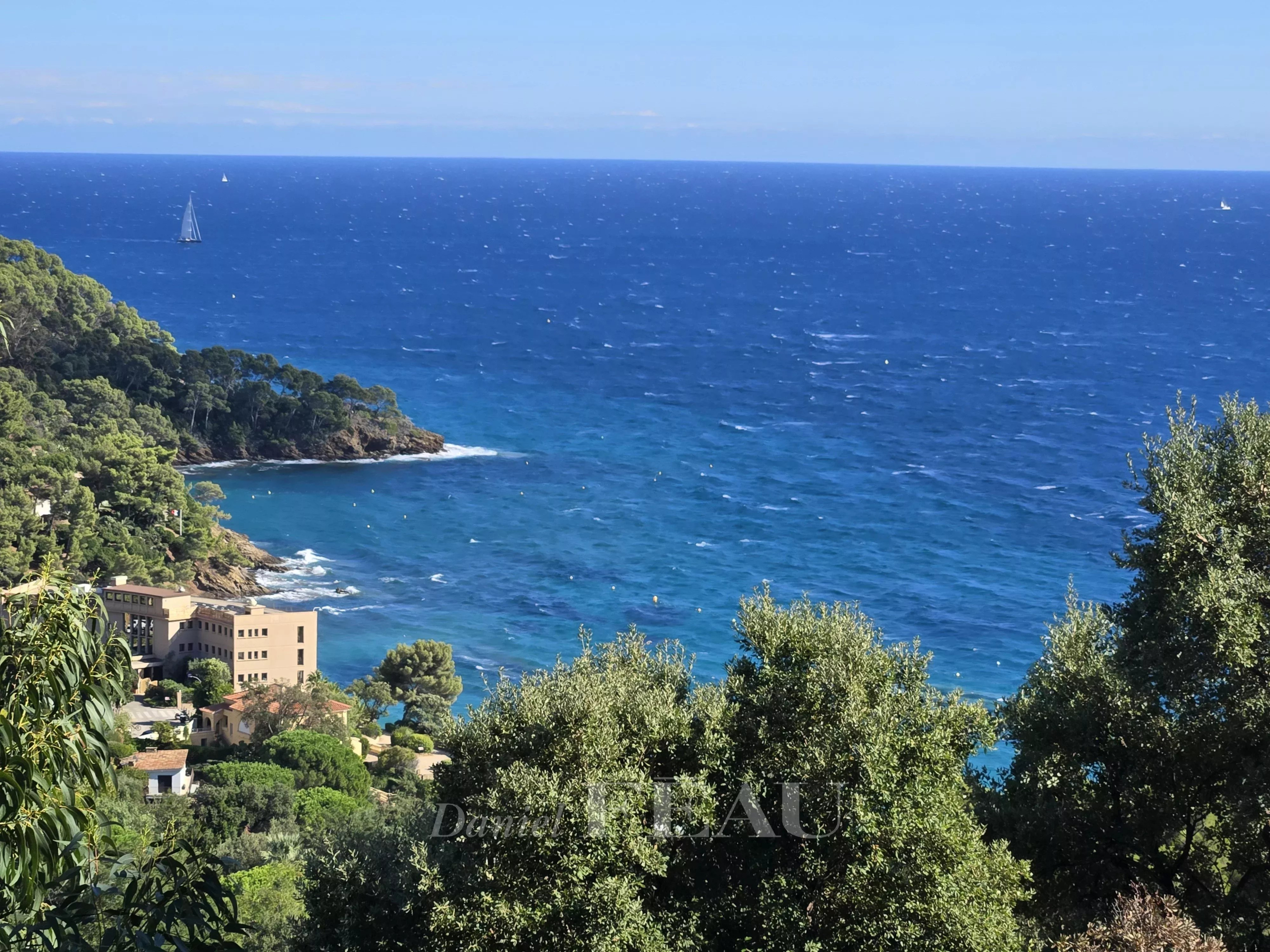 Vue panoramique sur la mer depuis une propriété à Rayol-Canadel-sur-Mer, avec des arbres au premier plan.