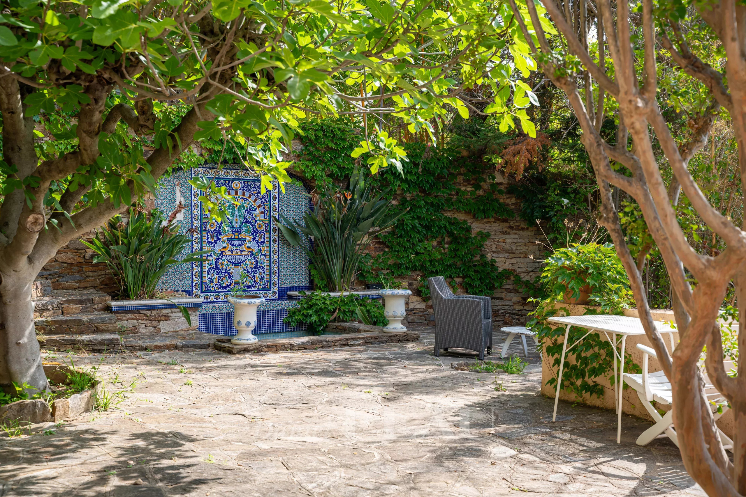 Jardin d'une propriété à Rayol-Canadel avec des plantes, une décoration murale et des meubles de jardin.