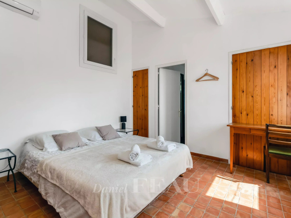 Chambre d'une villa à Rayol-Canadel, avec lit double, murs blancs et bois, bureau en bois.