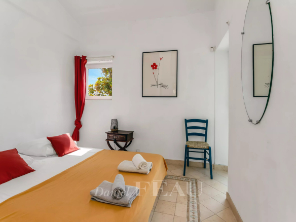 Chambre d'une villa à Rayol-Canadel avec lit, décoration simple et vue sur l'extérieur.
