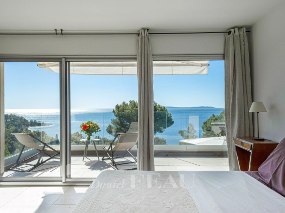 Vue panoramique sur la mer depuis une chambre avec lit et terrasse à Le Lavandou.