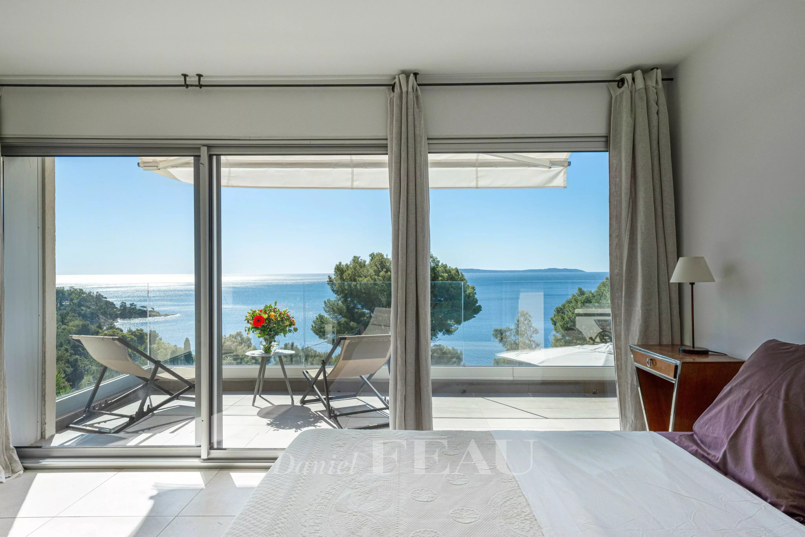 Vue panoramique sur la mer depuis une chambre avec lit et terrasse à Le Lavandou.