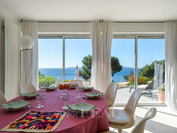 Intérieur d'une propriété à Le Lavandou avec vue sur la mer, table dressée et grandes baies vitrées.