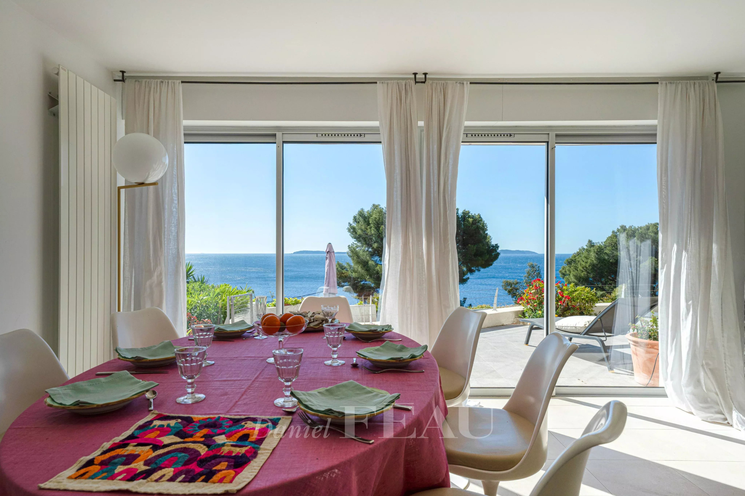 Intérieur d'une propriété à Le Lavandou avec vue sur la mer, table dressée et grandes baies vitrées.