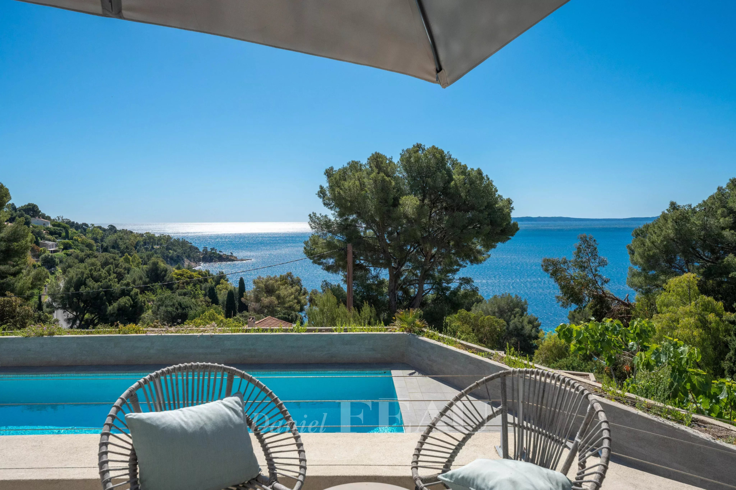 Vue panoramique sur la mer depuis une terrasse avec des chaises en osier au Lavandou.