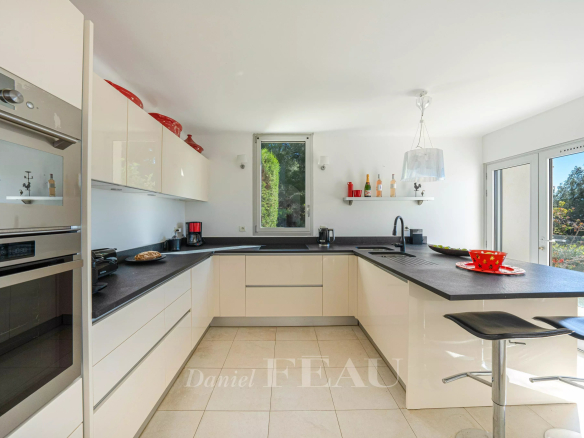 Cuisine moderne et lumineuse avec plan de travail noir et équipements intégrés.