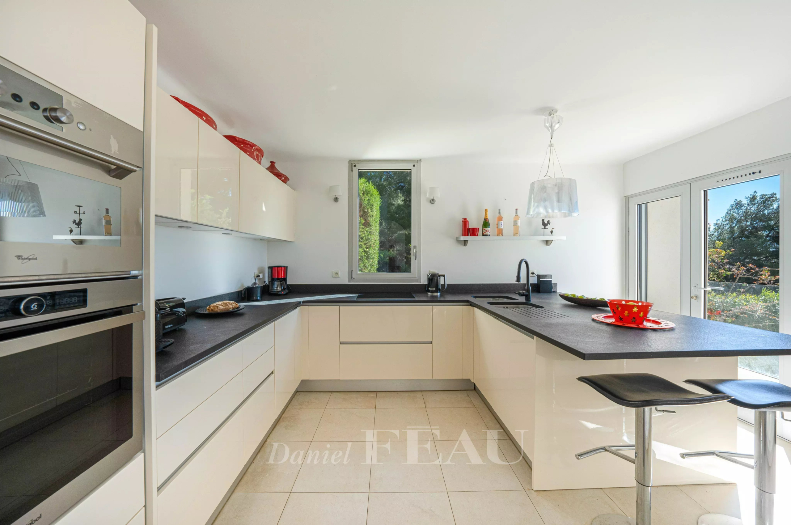 Cuisine moderne et lumineuse avec plan de travail noir et équipements intégrés.