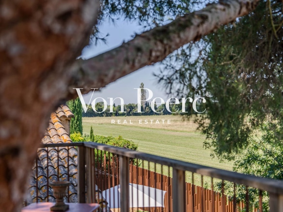 Vue d'un mas provençal rénové avec un parc paysager à Arles, entouré de prairies et d'arbres.