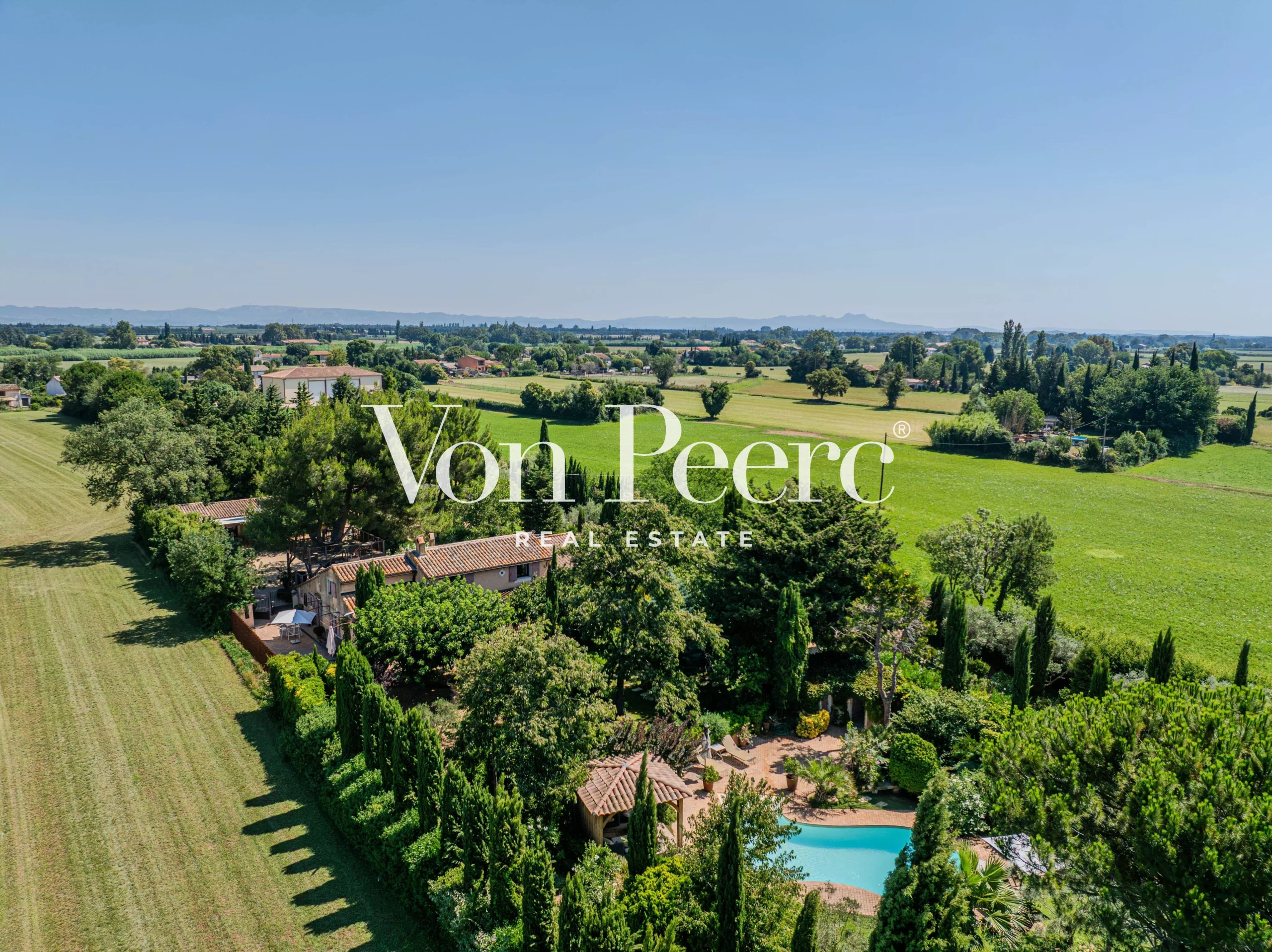 Vue aérienne d'un mas provençal rénové avec parc paysager à Arles, entouré de prairies et de paysages méditerranéens.