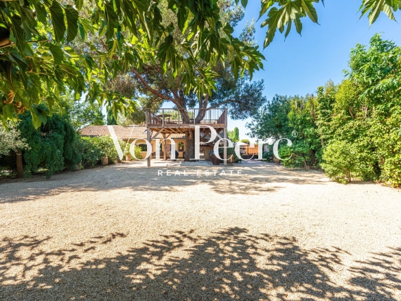 Mas provençal rénové avec parc paysager à Arles, entouré d'arbres et de verdure.