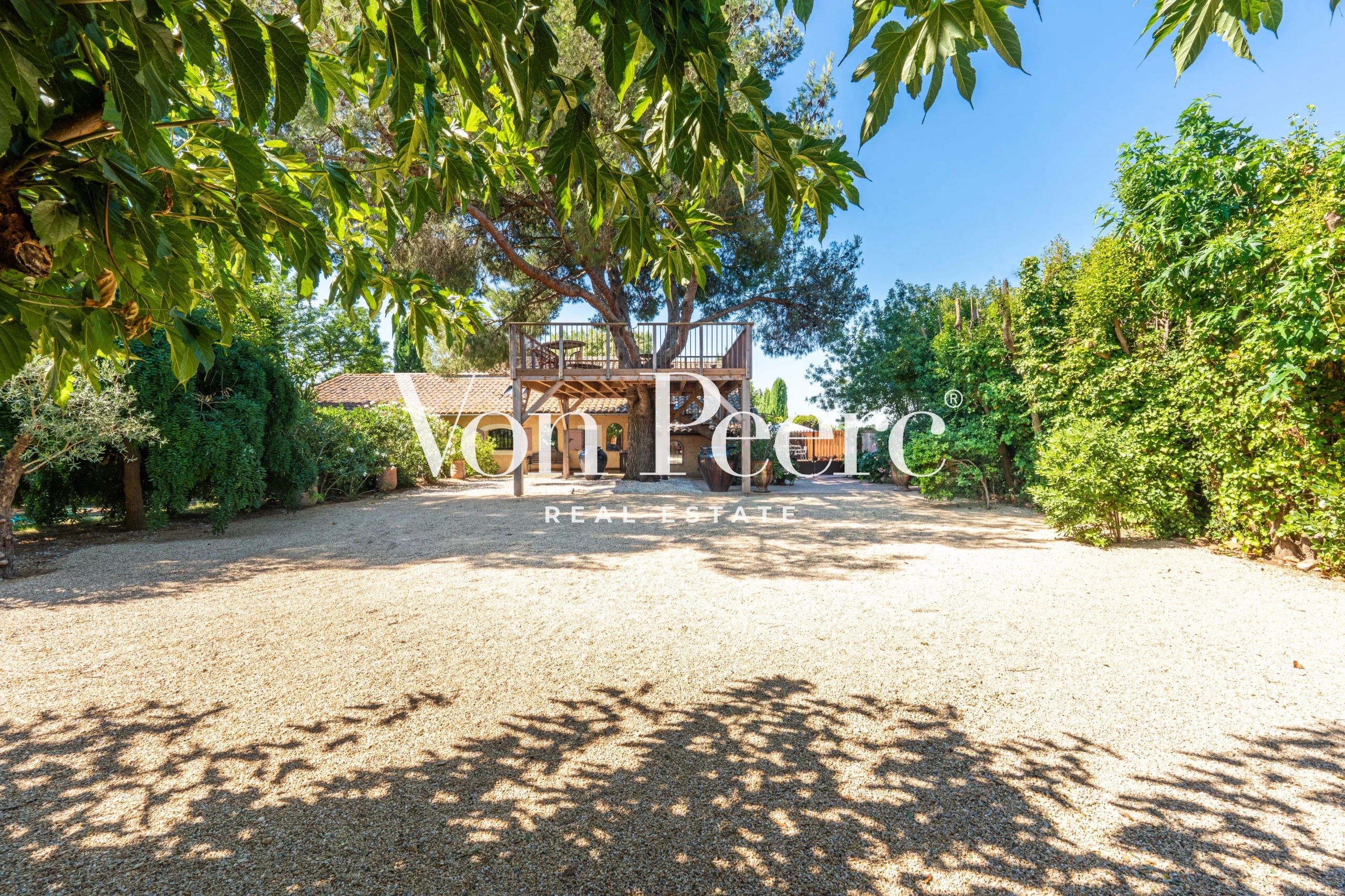Mas provençal rénové avec parc paysager à Arles, entouré d'arbres et de verdure.