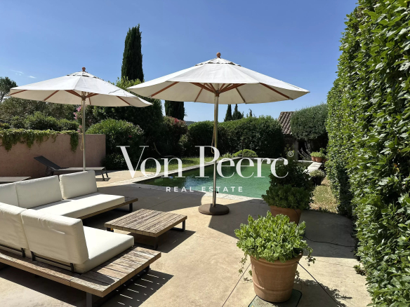 Terrasse avec parasols et piscine dans un jardin arboré.