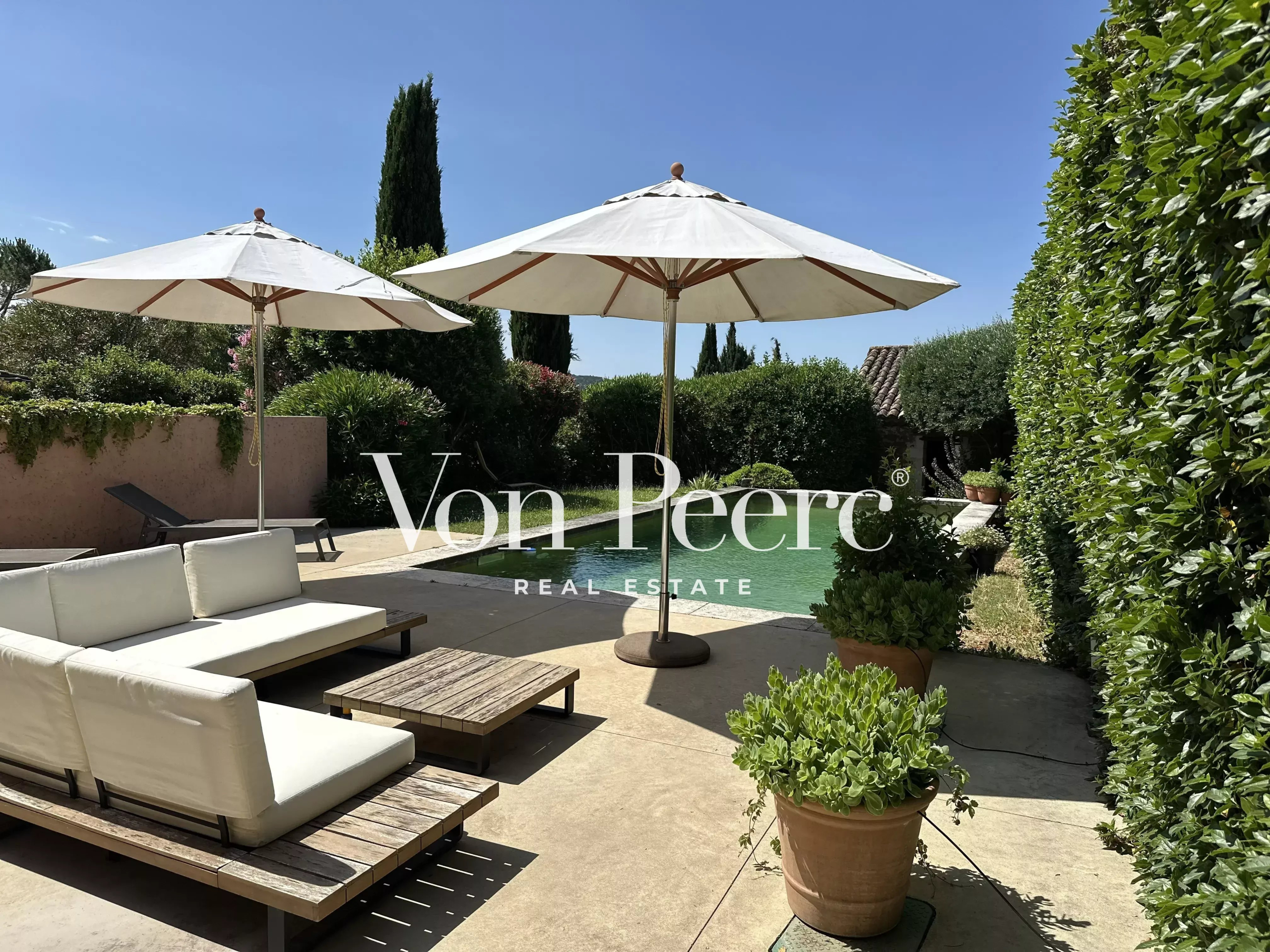 Maison avec jardin et piscine à Pujaut Terrasse avec parasols et piscine dans un jardin arboré.