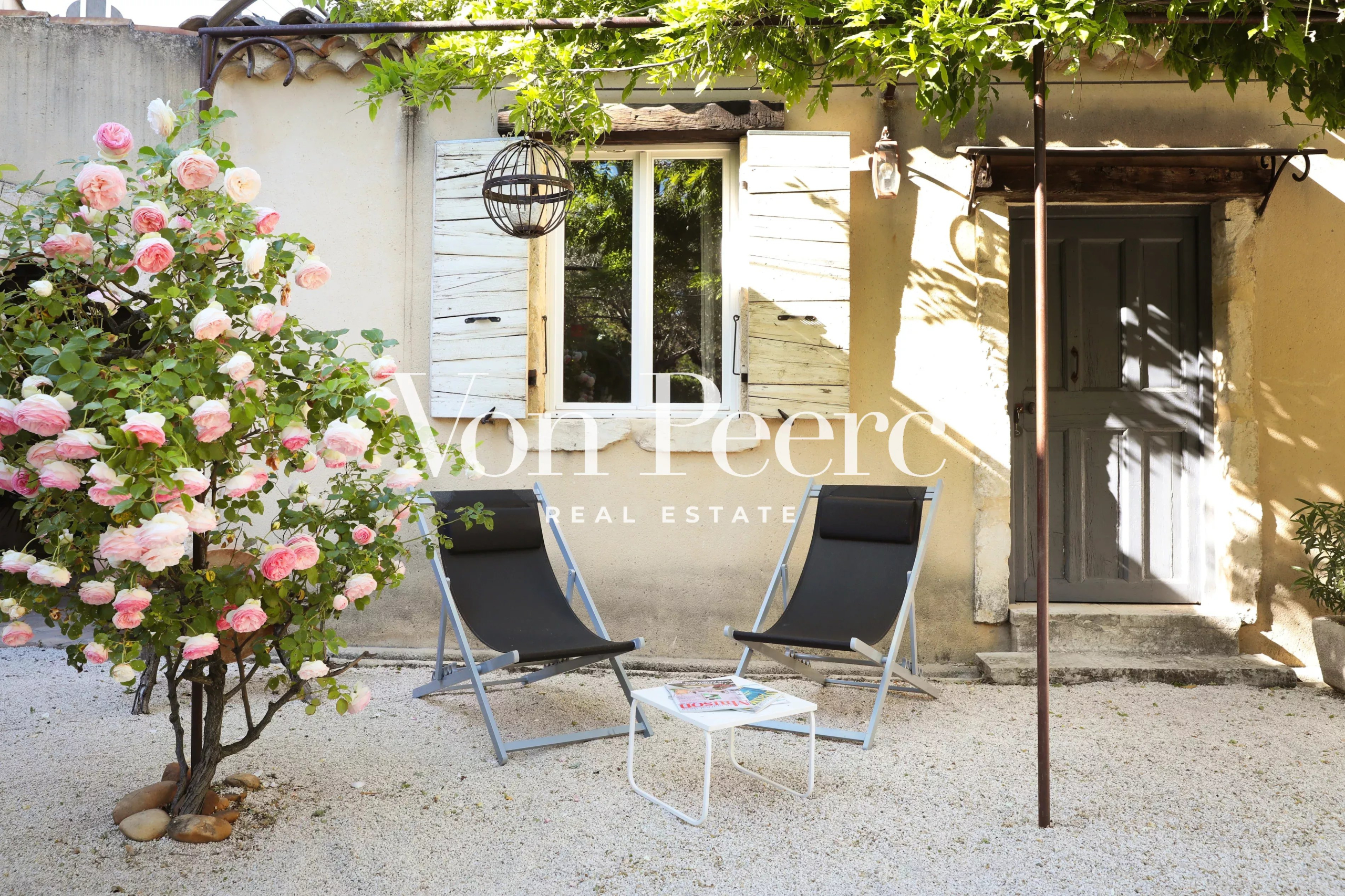 Terrasse d'une maison de caractère avec chaises longues et rosier, Saint-Laurent-des-Arbres.