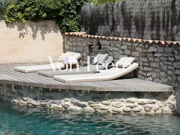 Terrasse en bois avec chaises longues au bord d'une piscine.