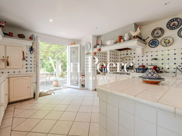 Cuisine lumineuse d'une maison provençale avec carrelage et accès à l'extérieur.