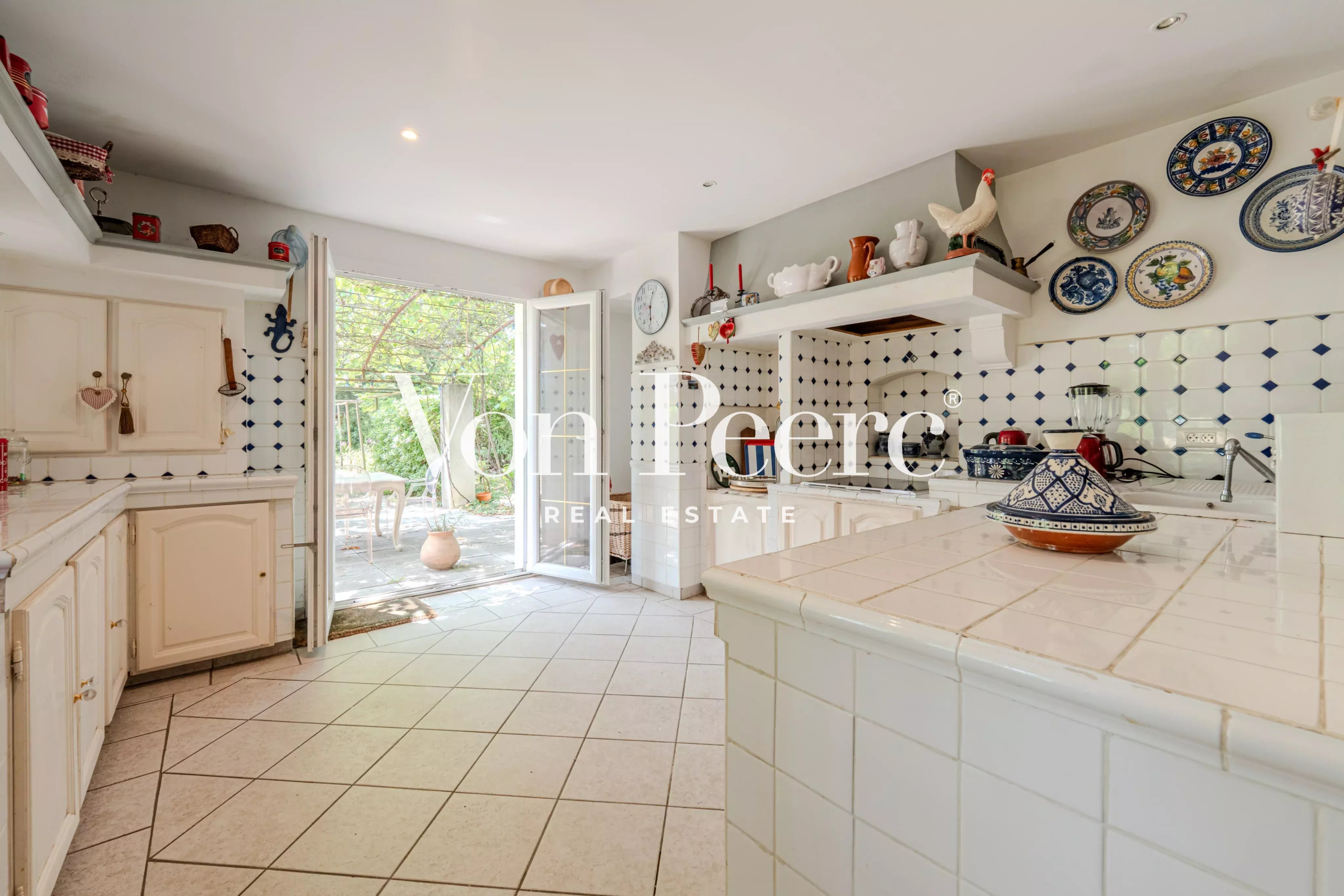 Cuisine lumineuse d'une maison provençale avec carrelage et accès à l'extérieur.