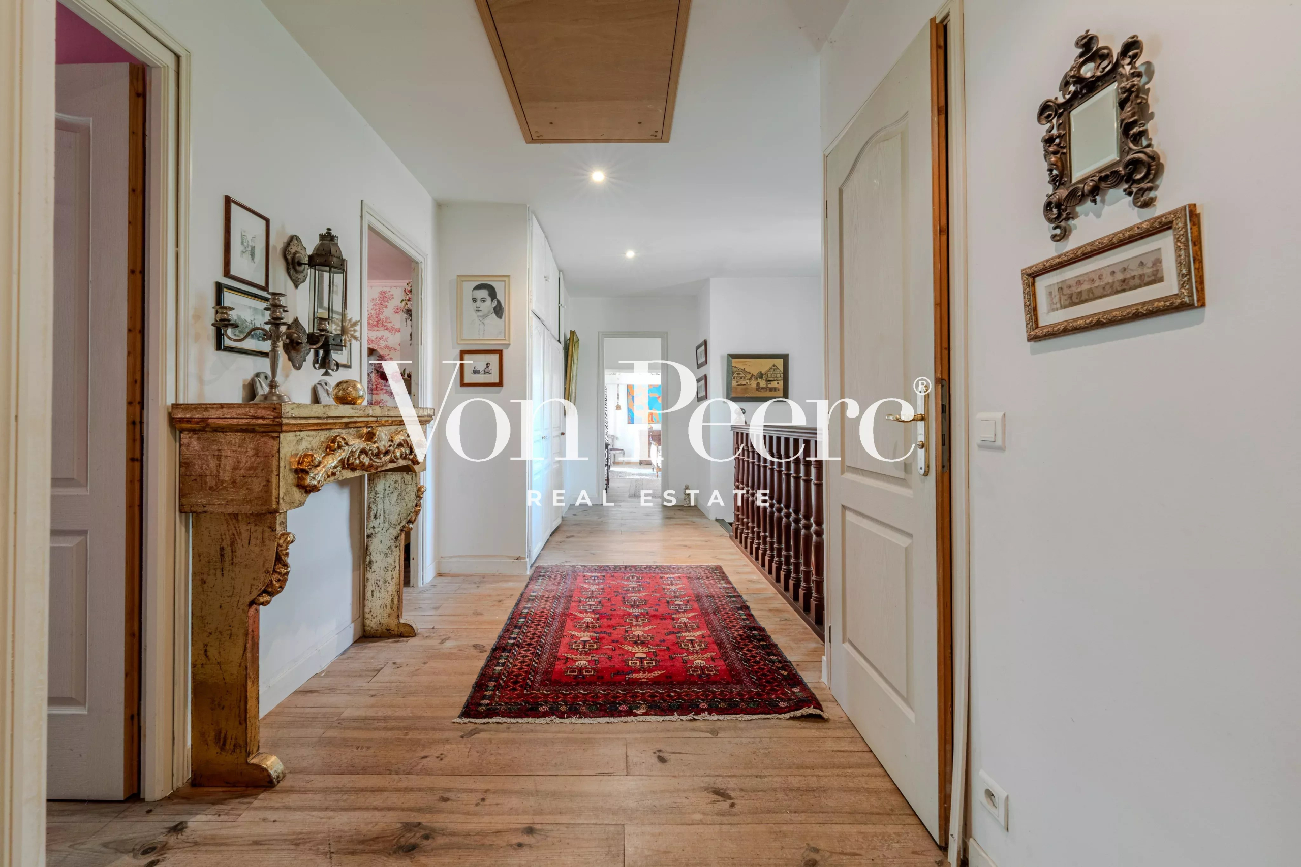 Intérieur d'une maison provençale avec un couloir décoré et un tapis rouge.
