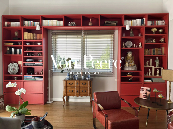 Intérieur d'une maison avec bibliothèque rouge, fauteuils et décoration élégante.