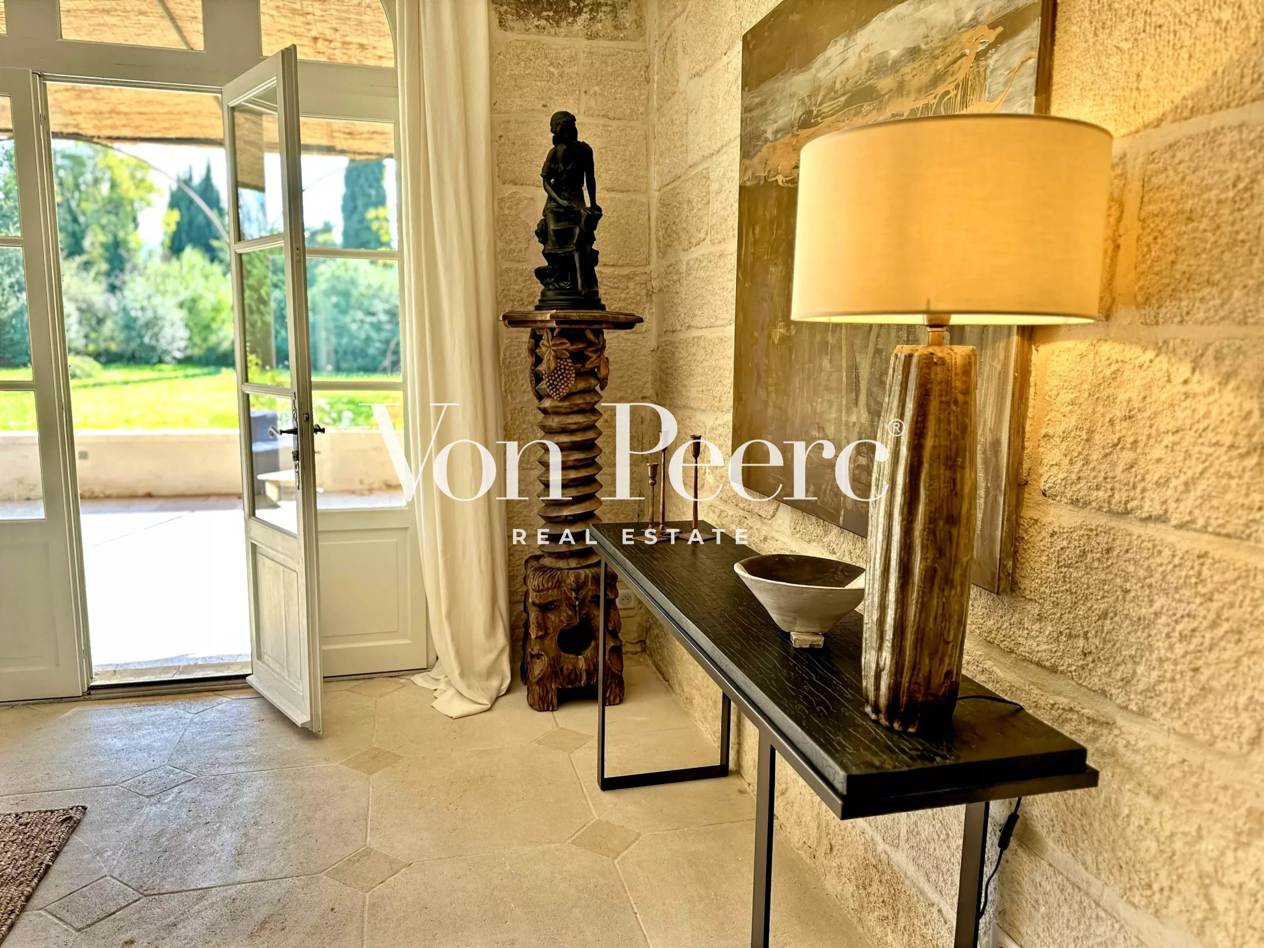 Intérieur d’une maison rénovée à Saint-Rémy-de-Provence Intérieur d'une maison ancienne rénovée avec un meuble décoratif et une lampe, vue sur le jardin.