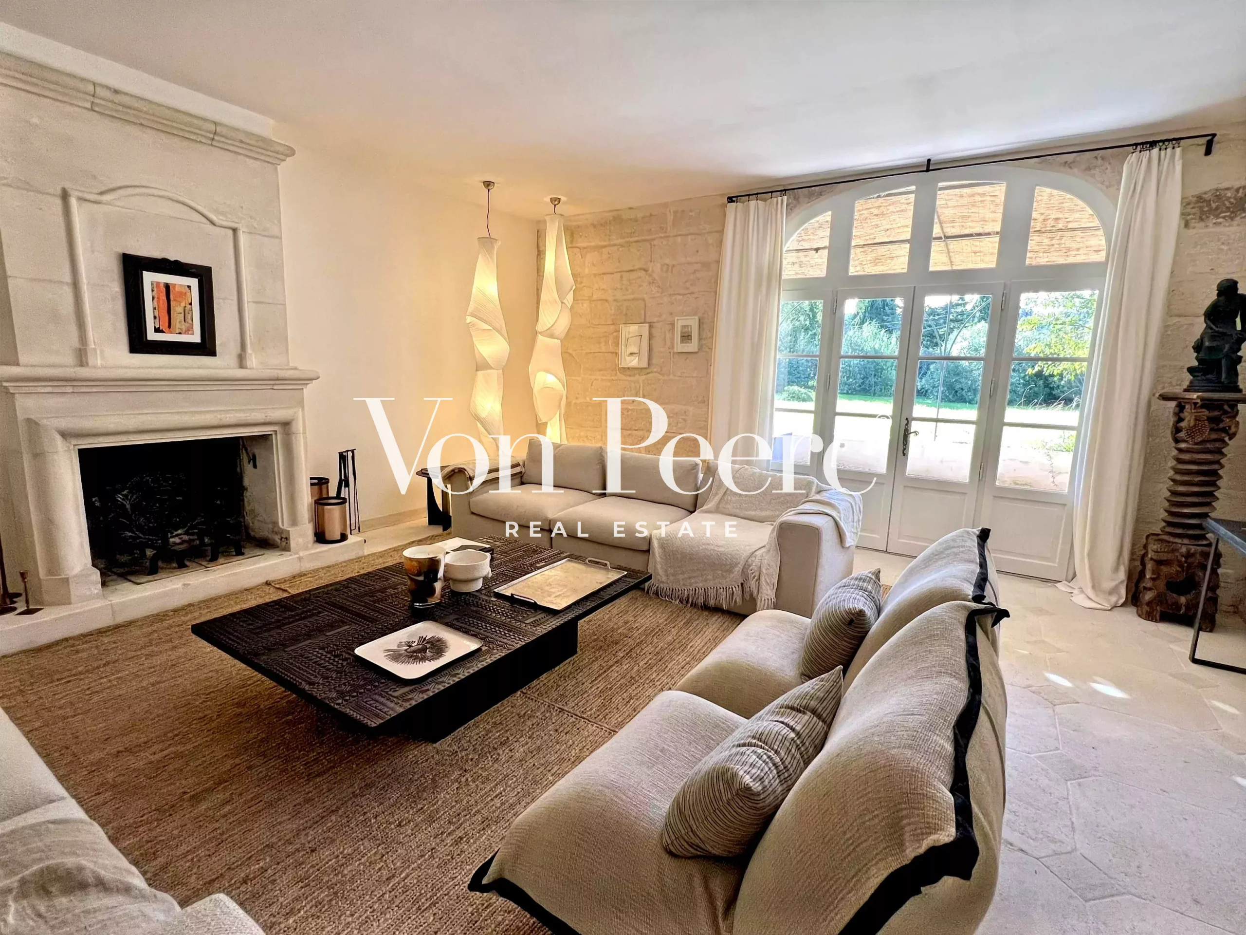 Salon d’une maison rénovée à Saint-Rémy-de-Provence Intérieur d'une maison ancienne rénovée avec un salon lumineux, cheminée et accès au jardin.