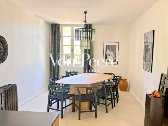 Intérieur d'une maison rénovée avec une grande table à manger et des chaises, style moderne.