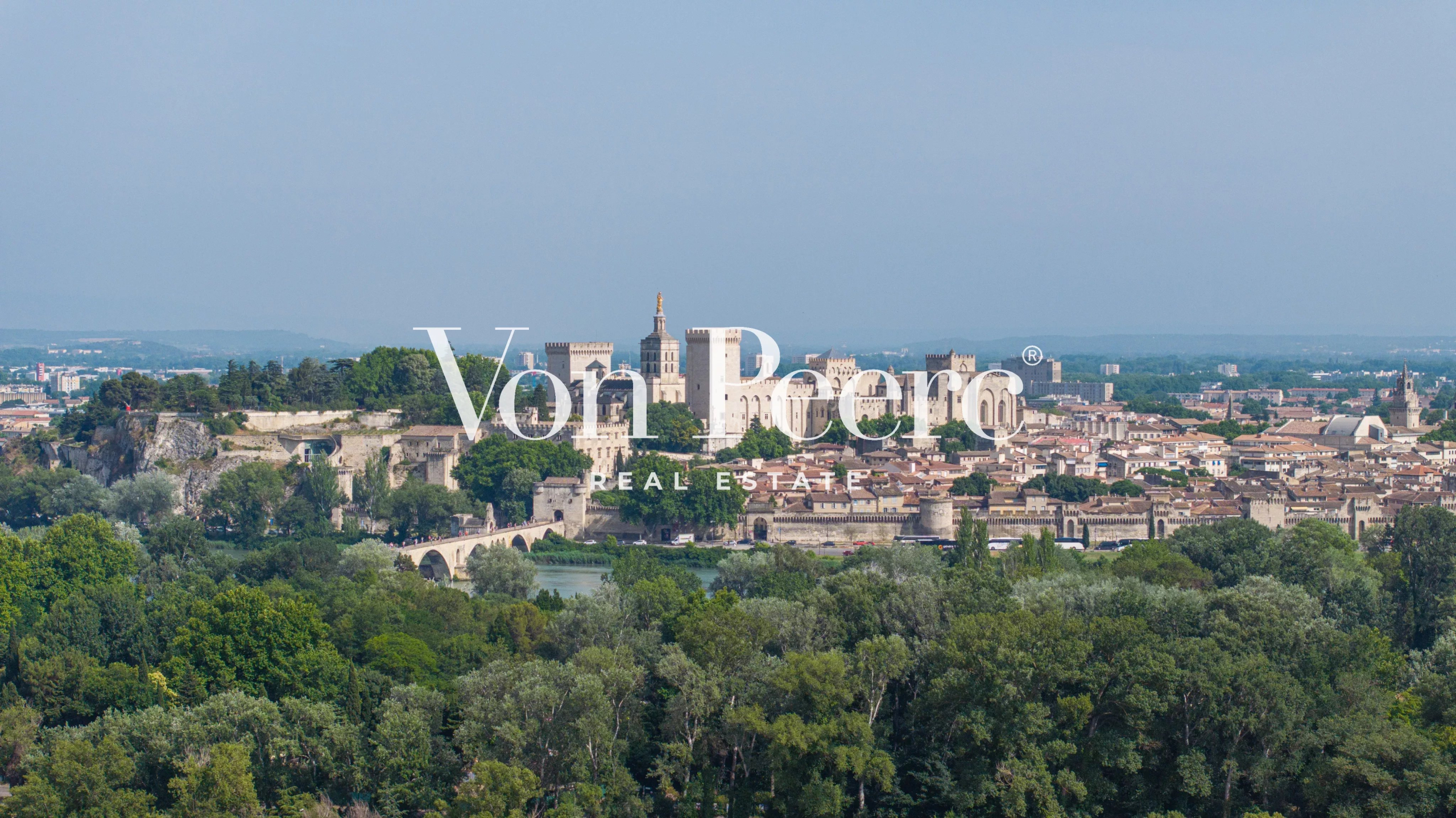 Land with a view of Avignon Panoramic view of Avignon, including the Palais des Papes and the Tour Philippe Le Bel, from a wooded area.