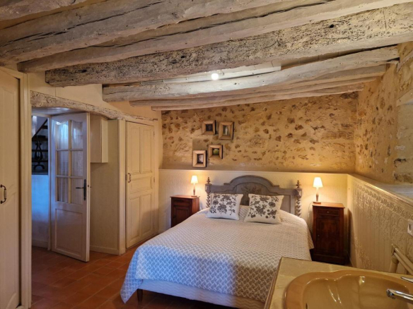 Chambre d'une propriété en pierres avec lit double et murs en pierre apparente.