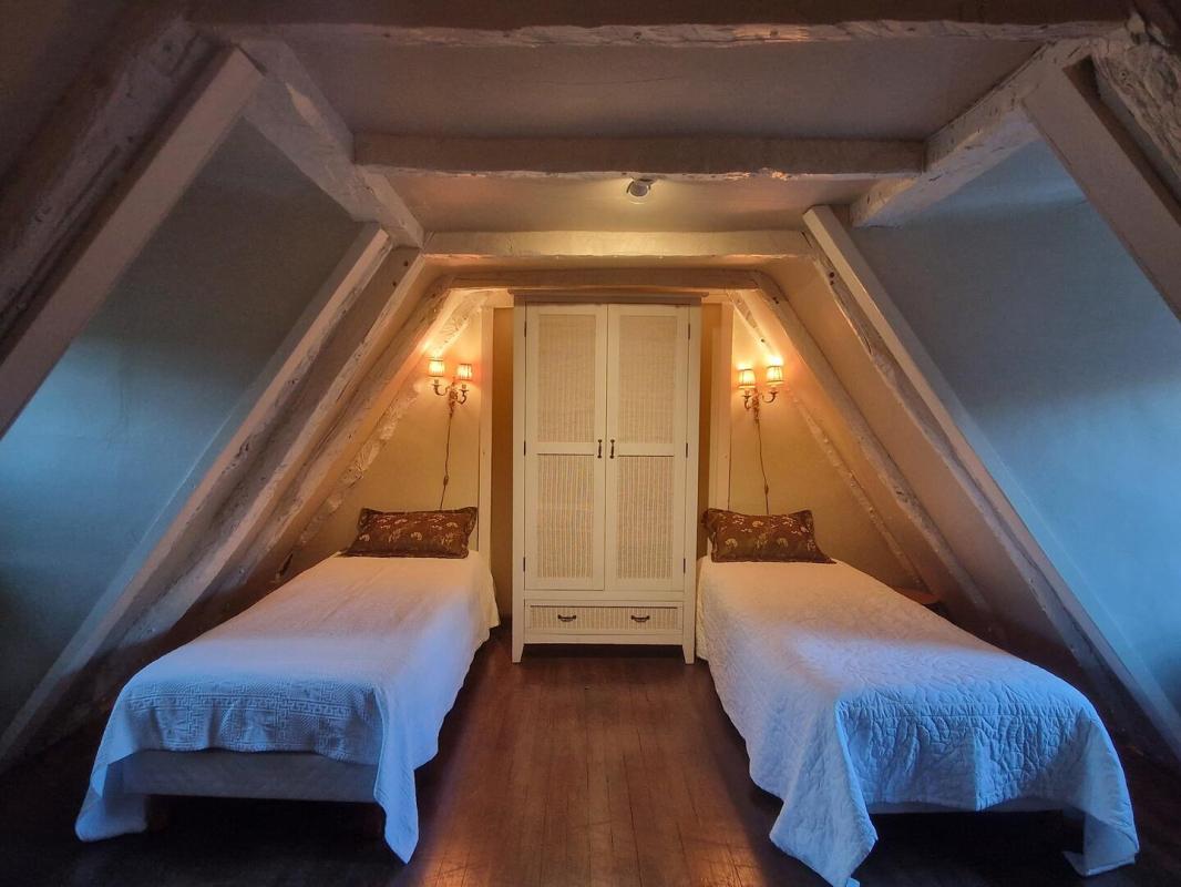 Chambre sous combles Chambre avec deux lits simples sous un plafond en pente et un meuble de rangement.