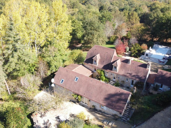 Vue aérienne d'une propriété en pierres avec piscine et terrain arboré à Les Eyzies.