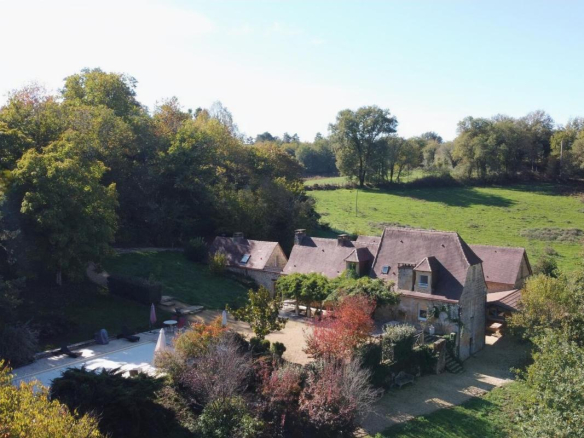 Vue aérienne d'une propriété en pierres avec piscine et terrain arboré à Les Eyzies