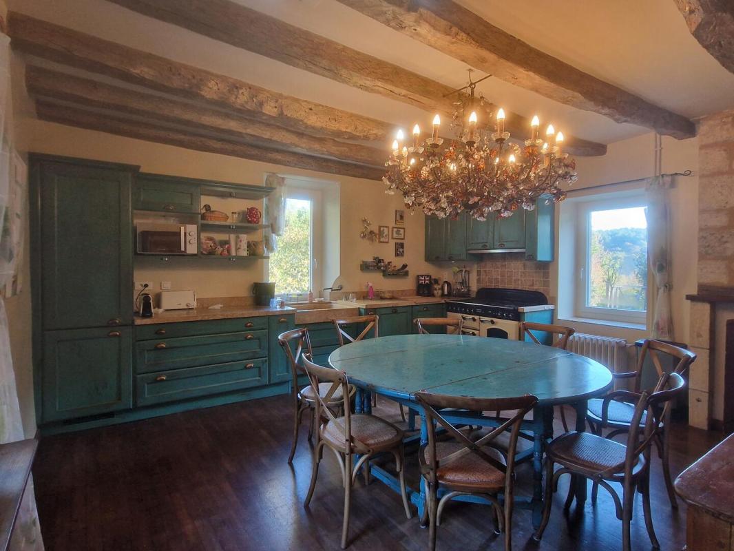 Cuisine spacieuse avec lustre Cuisine d'une maison en pierre avec un grand table et des chaises, éclairée par un lustre.