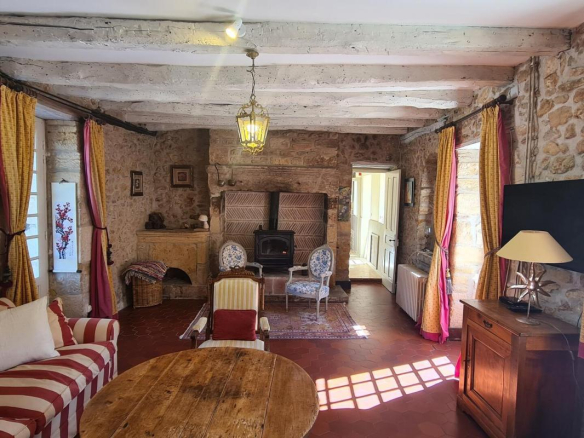 Intérieur d'une maison en pierre avec salon confortable et cheminée, décoré de meubles anciens.