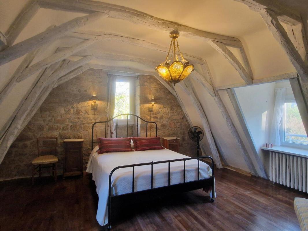 Chambre avec plafond en poutres apparentes Chambre d'une maison en pierre avec un plafond en poutres apparentes et un lit double.