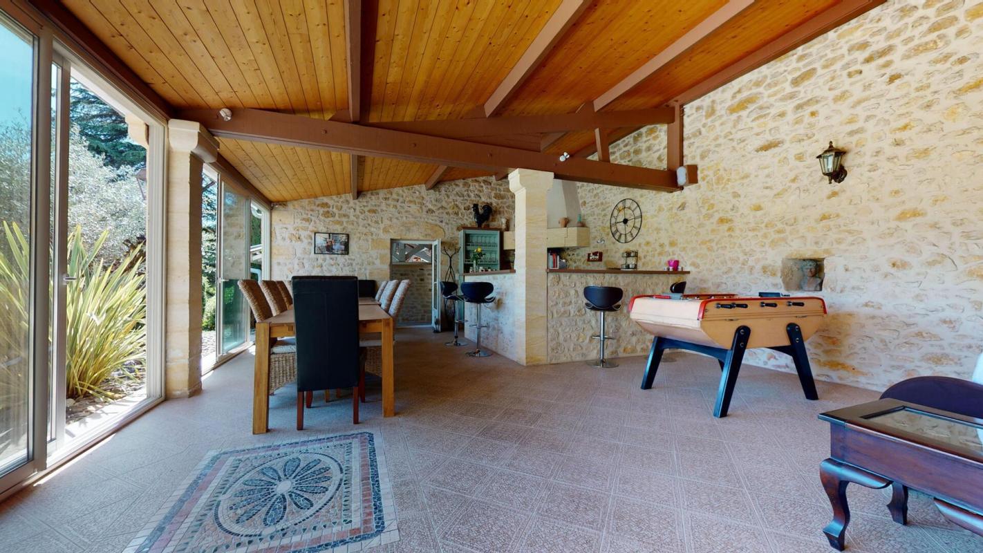 Intérieur d'une belle demeure en pierres avec un espace de vie lumineux et un baby-foot.