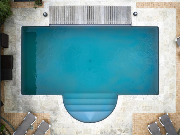 Vue aérienne d'une piscine avec terrasse, entourée de chaises longues.
