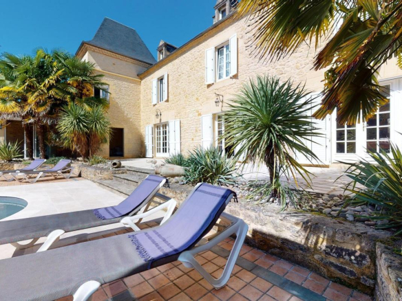 Demeure en pierres avec piscine et chaises longues, végétation luxuriante, Sarlat-la-Canéda