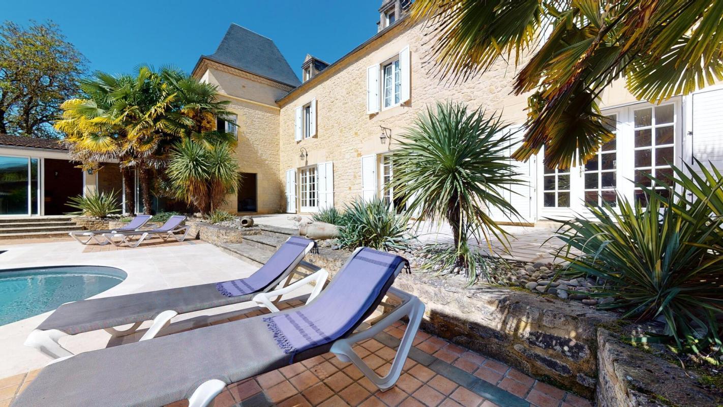 Demeure en pierres avec piscine et chaises longues, végétation luxuriante, Sarlat-la-Canéda