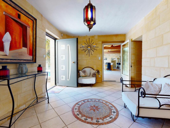 Intérieur d'une maison en pierres avec un hall d'entrée décoré et un tapis au sol.