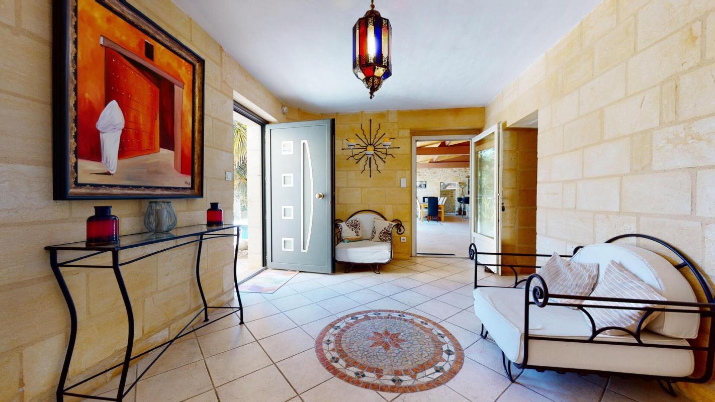 Intérieur d'une maison en pierres avec un hall d'entrée décoré et un tapis au sol.