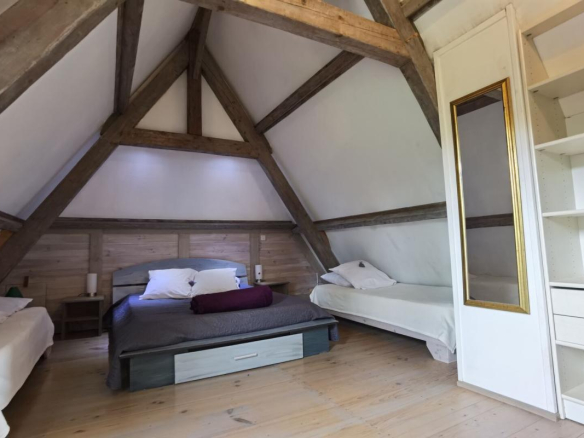 Attic room with exposed beams and single beds in Excideuil.