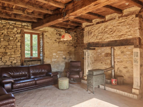 Interior of a stone farmhouse with a living room, stone walls and a stove.
