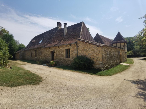 Stone farmhouse with barn and guest house, situated in a rural setting.