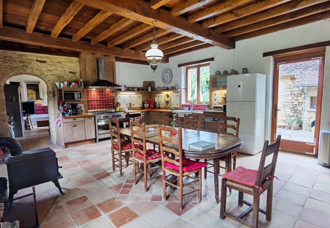 Farmhouse kitchen in Excideuil Interior of a rustic kitchen with a wooden table and chairs, stone walls and exposed beams.