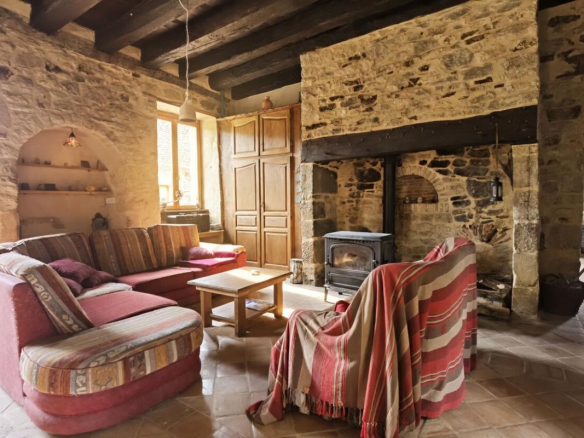Interior of a stone farmhouse with a cozy living room and a fireplace.