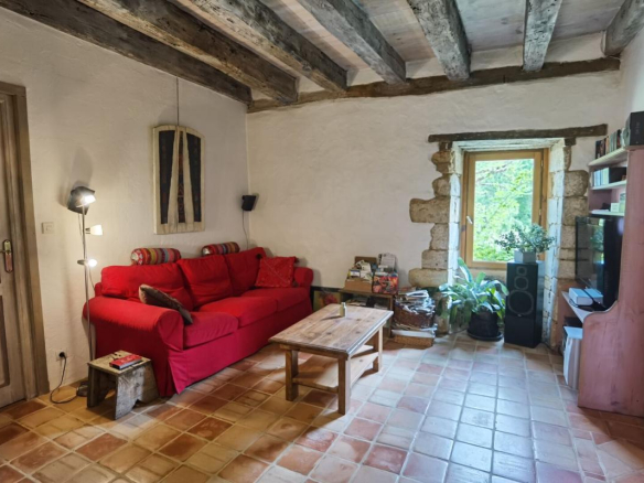 Interior of a living room with a red sofa, stone walls and exposed beams.
